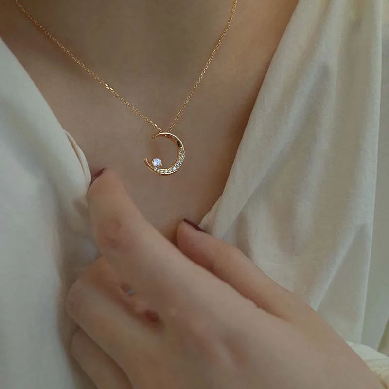 Gold necklace with a crescent moon pendant worn by a person